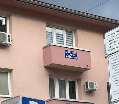 a pink building with a blue sign on it at Apartment Zara Bihac in Bihać
