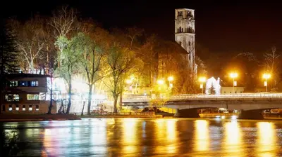 a bridge over a river at night with a clock tower at Apartment Zara Bihac in Bihać