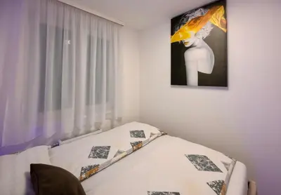 a bedroom with a bed with a picture on the wall at Apartman K&S in Banja Luka