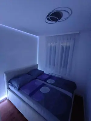 a small bedroom with a bed with a blue blanket at Apartman K&S in Banja Luka