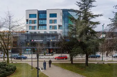 two people walking down a sidewalk in front of a building at Mona Visoko in Visoko