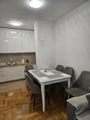 a dining room with a table and chairs and a kitchen at Apartment Zidart Banja Luka free garage in Banja Luka