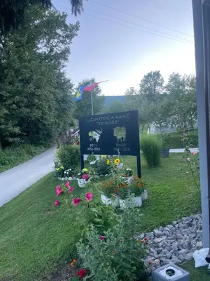 a sign in the grass with flowers in a yard at Vikendica u prirodi na ranču in Zolaći