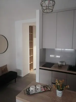 a kitchen with white cabinets and a table in a room at Apartman 33 in Banja Luka