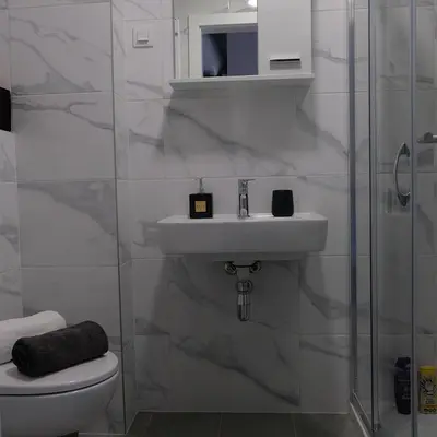 a white bathroom with a sink and a shower at Apartman 33 in Banja Luka
