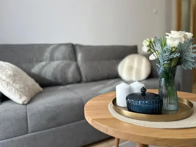 a living room with a couch and a table with flowers at Apartman Mona in Teslić