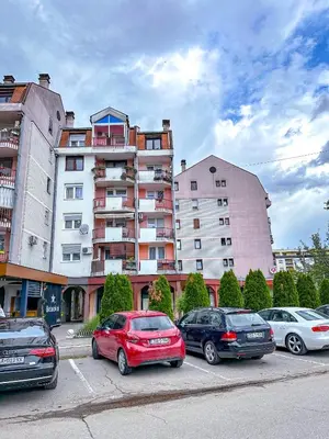 a parking lot with cars parked in front of a building at Apartman Mona in Teslić