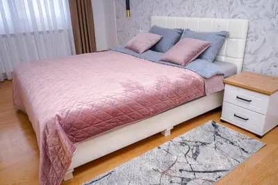 a bed with pink and blue sheets and a table at Apartman Mona in Teslić