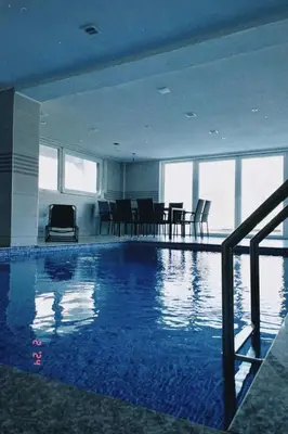 a large swimming pool in a building with a table and chairs at Villa SHAMS in Travnik