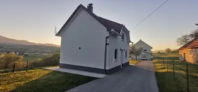 a white house with a black roof on a road at Fortuna in Livno