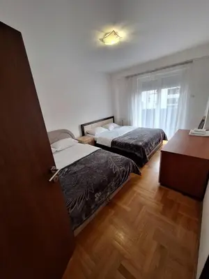 two beds in a room with a desk and a window at Luks 3 apartment in Banja Luka