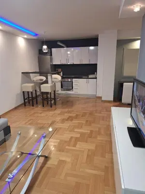 a kitchen and living room with a wooden floor at Luks 3 apartment in Banja Luka