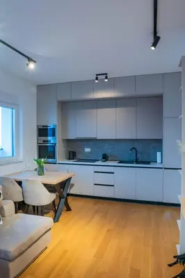 a kitchen with white cabinets and a wooden floor at Apartment ALPHA in Banja Luka