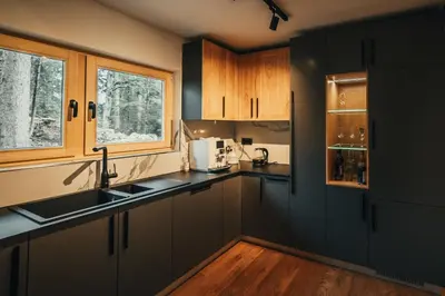a kitchen with black counters and wooden cabinets at The Cozy Chalet in Bosanski Petrovac
