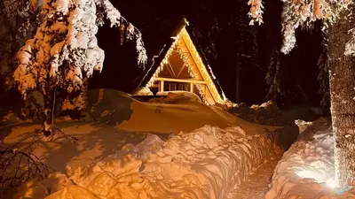 a cabin covered in snow at night with lights at The Cozy Chalet in Bosanski Petrovac