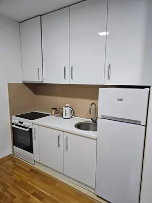 a kitchen with white cabinets and a sink and a refrigerator at Apartman 36 Banja Luka in Banja Luka