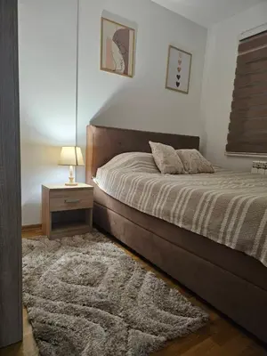 a bedroom with a large bed and a nightstand with a lamp at Apartman 36 Banja Luka in Banja Luka