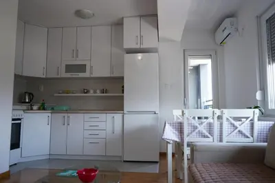 a kitchen with white cabinets and a table and chairs at Apartman KoprenaZ in Banja Luka