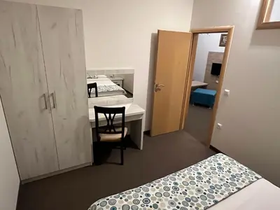 a room with two beds and a desk and a chair at Apartmani Villa Grande in Bugojno