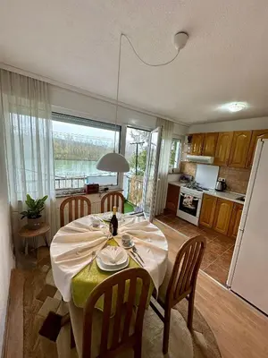 a dining room with a table and a kitchen at Stan na dan Kej Una in Bosanska Dubica