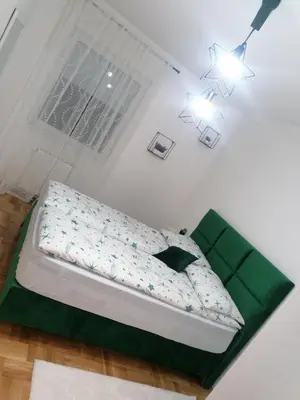 a bedroom with a bed with green sheets and a window at Stan 23 in Banja Luka