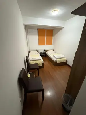 a small room with two beds and a chair at Hotel Avanti in Zenica