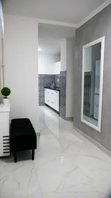 a living room with a black ottoman and a mirror at Apartman PLATINUM in Doboj