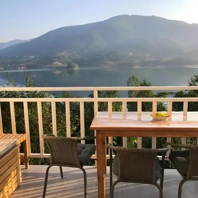 a table and chairs on a deck with a view of a lake at Apartman Manov - Ramsko jezero in Prozor