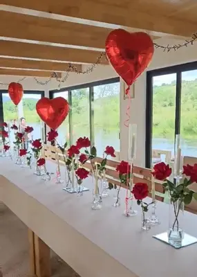 a table with red roses in vases and hearts at Guest House Šobić in Šipovo