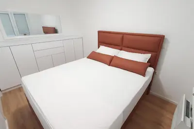 a small white bedroom with a bed and a window at West Wing - Apartmani Živinice in Živinice