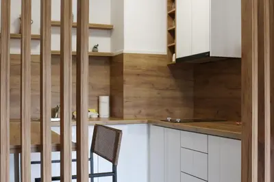 a kitchen with white cabinets and a wooden wall at West Wing - Apartmani Živinice in Živinice