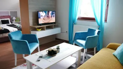 a living room with two chairs and a table and a tv at Kuća za Odmor Naša Priča in Šipovo