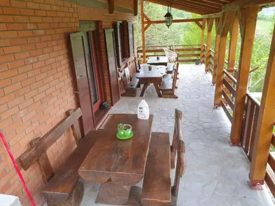 a patio with wooden benches and tables on a building at Kuća za Odmor Naša Priča in Šipovo
