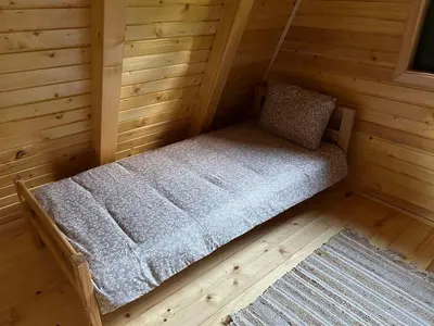 a small bed in a wooden cabin with a rug at Villa Forest Paradise in Visoko
