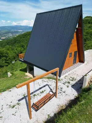 a house with a black roof and a swing at Villa Forest Paradise in Visoko