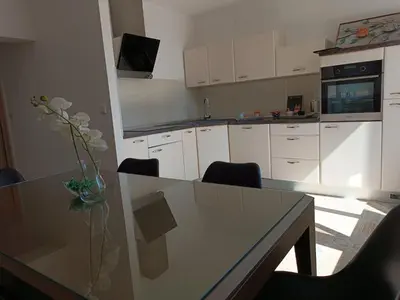 a kitchen with a table with a vase of flowers on it at Apartman Slatina in Tuzla