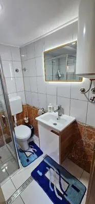 a bathroom with a sink and a toilet and a mirror at Sobe Amar in Tuzla