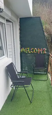 a chair on a balcony with a table and flowers at Apartman Heli Meli 1 in Jajce