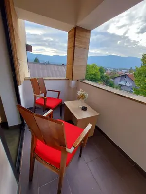 a balcony with two chairs and a table and a window at Hotel Irish in Bihać