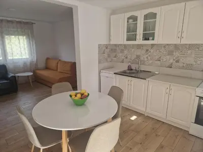 a kitchen and a table with a bowl of fruit on it at Sofija, Guests House in Ključ