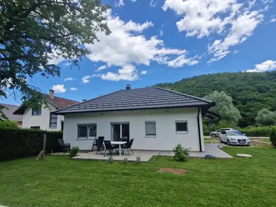a white house with a table and chairs in a yard at Sofija, Guests House in Ključ