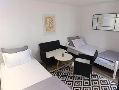 a small room with two beds and a table and chairs at VA Apartments in Tešanj