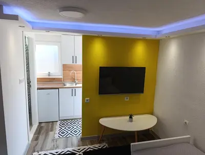 a kitchen with a yellow wall with a tv on it at VA Apartments in Tešanj