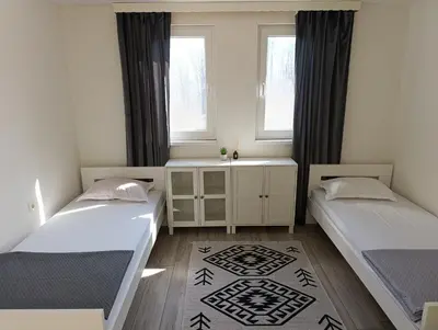 two beds in a room with two windows at VA Apartments in Tešanj