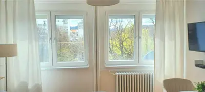 a living room with three windows and a television at Plavi studio in Banja Luka
