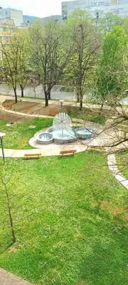 a park with benches and a fountain in the grass at Plavi studio in Banja Luka