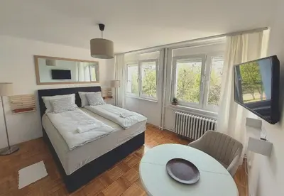 a bedroom with a bed and a table and some windows at Plavi studio in Banja Luka
