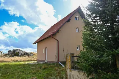 a small house in a field with a tree at Apartman Lena in Kupres