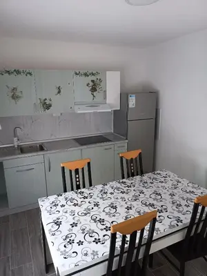 a kitchen with a table and chairs and a kitchen with a counter at Apartman Centar A in Modriča