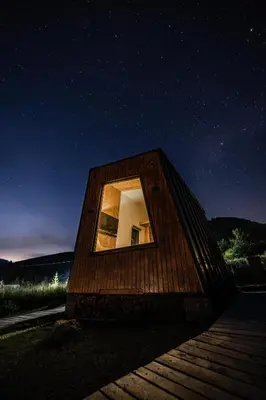 a small wooden building with a window at night at Tiny Glamp House - DANGUBA by IGLENA in Kupres